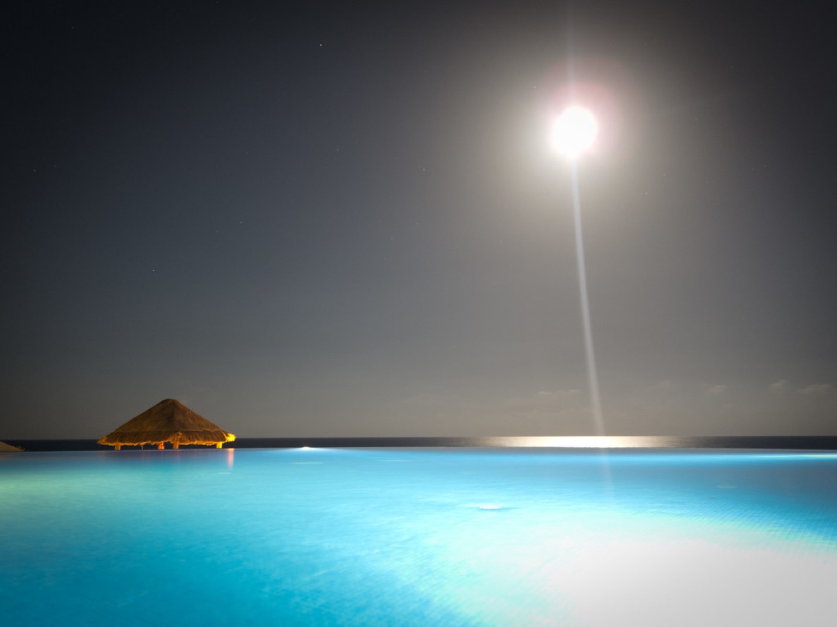 Cancun beach at night with glowing lights and turquoise water