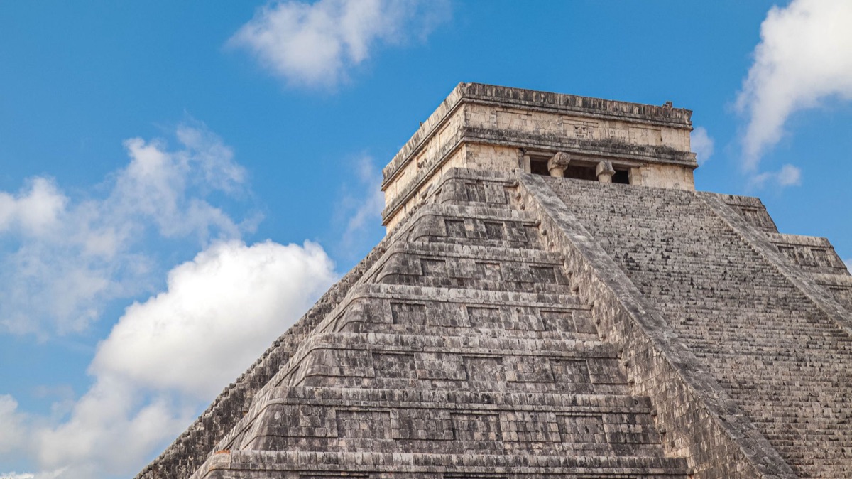 Píramides de Chichen Itza ao amanhecer, com luz dourada e sombras alongadas.