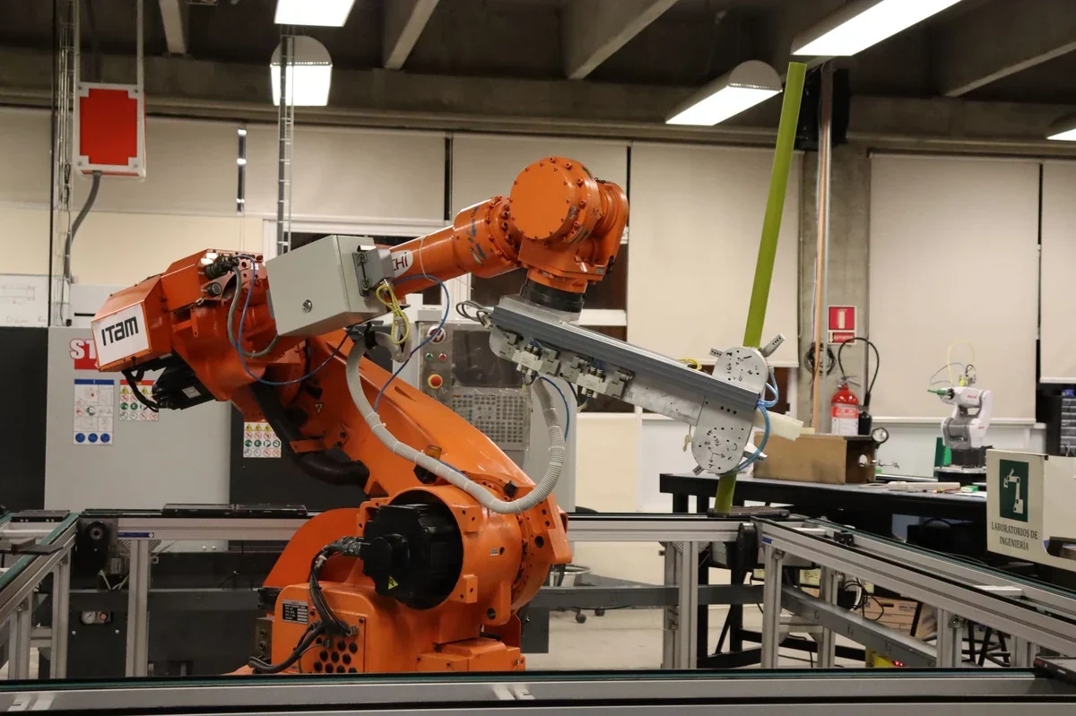 Großer orangefarbener Industrieroboterarm bewegt sich neben einem Fabrikförderband